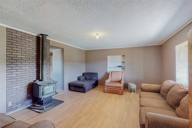 living room with crown molding, a textured ceiling, light hardwood / wood-style floors, and a wood stove