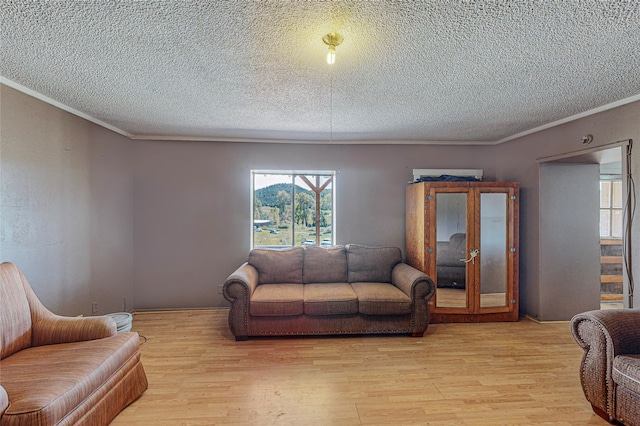 living room with a textured ceiling, crown molding, and light hardwood / wood-style floors