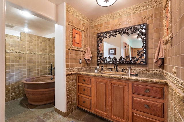 bathroom featuring tile walls, vanity, tile patterned floors, and a bathing tub