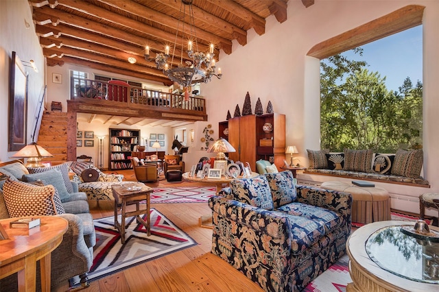 living room with wood ceiling, a towering ceiling, a notable chandelier, beamed ceiling, and light wood-type flooring