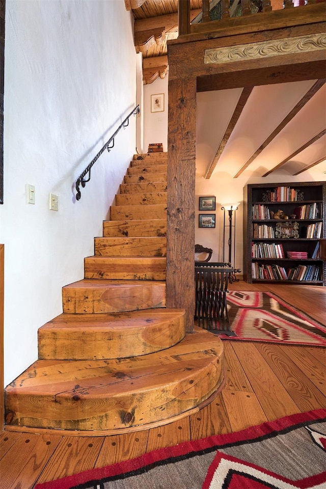 stairs featuring hardwood / wood-style floors and beam ceiling