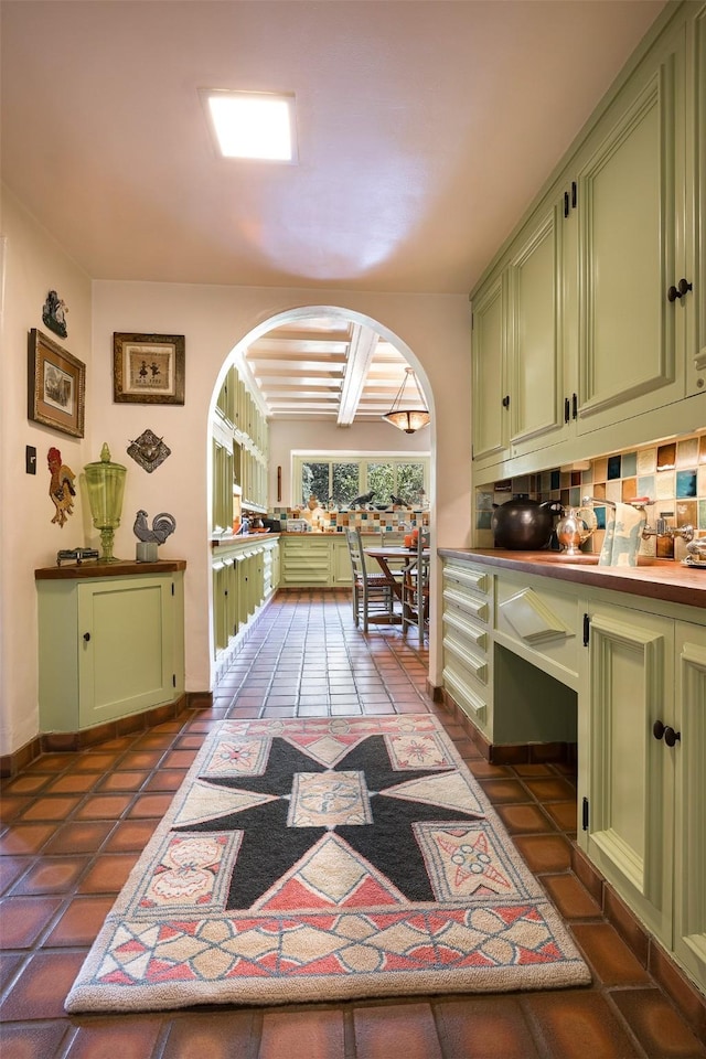 kitchen with tasteful backsplash, green cabinetry, and dark tile patterned floors