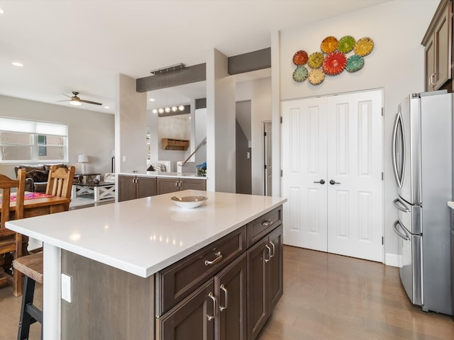 kitchen featuring ceiling fan, wood-type flooring, dark brown cabinetry, and stainless steel refrigerator