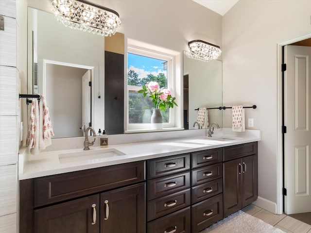 bathroom featuring dual bowl vanity, tile patterned flooring, and an inviting chandelier