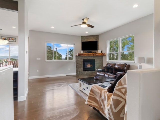 living room with hardwood / wood-style floors, a stone fireplace, and ceiling fan