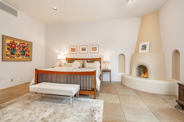 bedroom with a large fireplace and tile patterned flooring