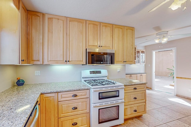 kitchen featuring ceiling fan, light stone countertops, white range with gas stovetop, and light brown cabinets