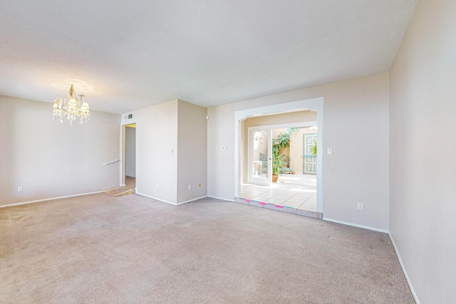 carpeted empty room featuring a chandelier