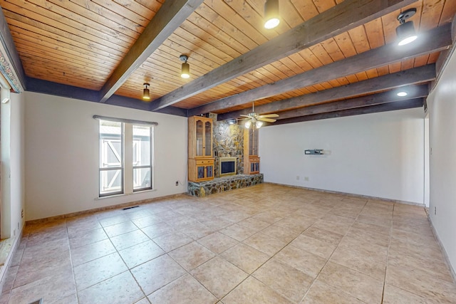 unfurnished living room with ceiling fan, beamed ceiling, a fireplace, and wood ceiling