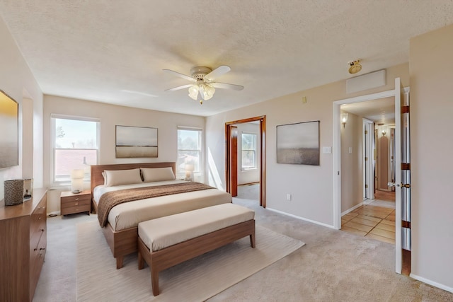 bedroom with ceiling fan, light colored carpet, a textured ceiling, and multiple windows