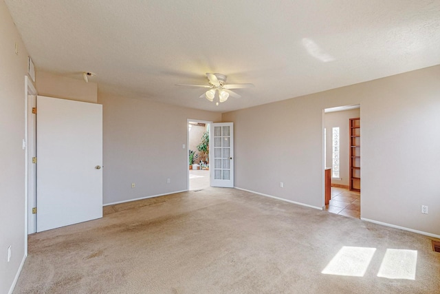 spare room featuring a textured ceiling, light carpet, and ceiling fan