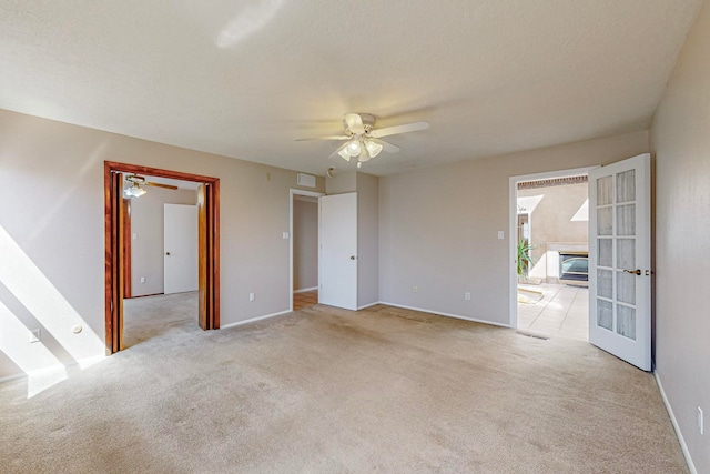 carpeted empty room with ceiling fan and french doors