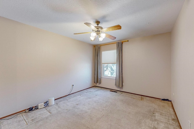 unfurnished room featuring ceiling fan, light colored carpet, and a textured ceiling