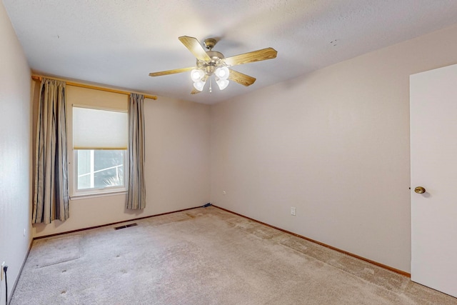 spare room with light carpet, ceiling fan, and a textured ceiling