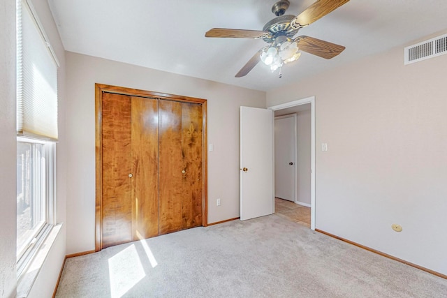 unfurnished bedroom featuring ceiling fan, a closet, and light carpet