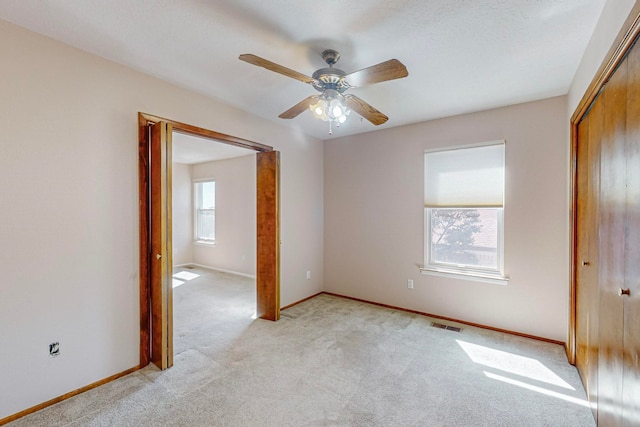 unfurnished bedroom with ceiling fan and light colored carpet