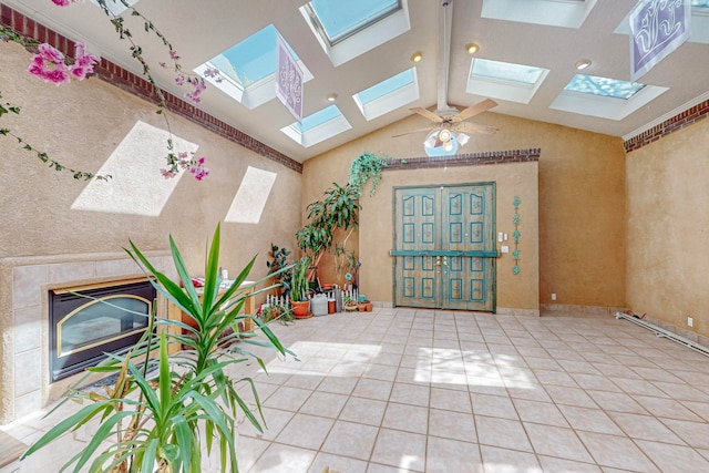 tiled entryway with vaulted ceiling with skylight and ceiling fan