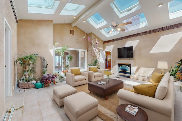 tiled living room featuring beam ceiling, a skylight, and ceiling fan