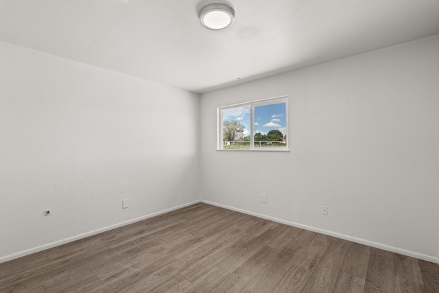 spare room featuring baseboards and wood finished floors
