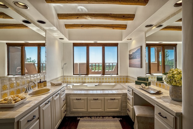 bathroom with hardwood / wood-style floors, beamed ceiling, decorative backsplash, vanity, and a washtub