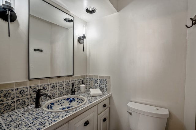 bathroom featuring toilet, decorative backsplash, and vanity