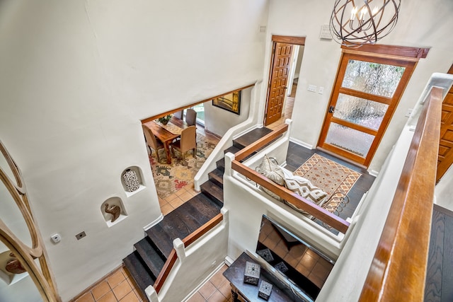 stairs with a healthy amount of sunlight, a chandelier, and tile patterned floors