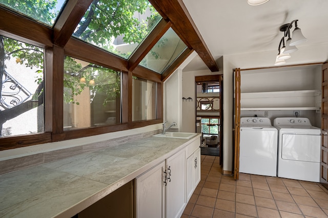 laundry area featuring sink, washing machine and clothes dryer, plenty of natural light, and a skylight