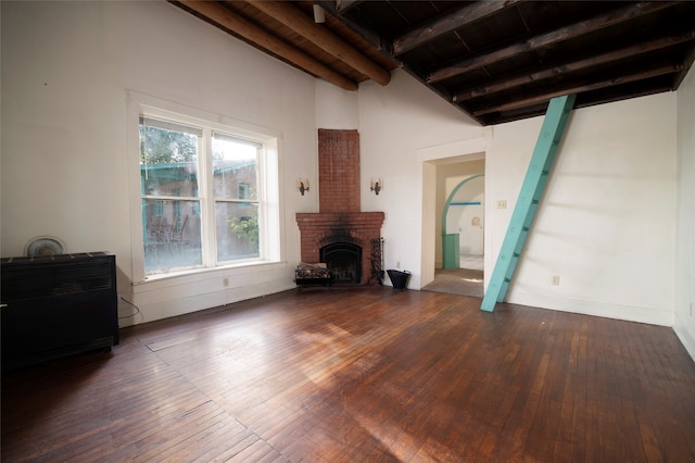 unfurnished living room with beamed ceiling, a brick fireplace, wood ceiling, and wood-type flooring