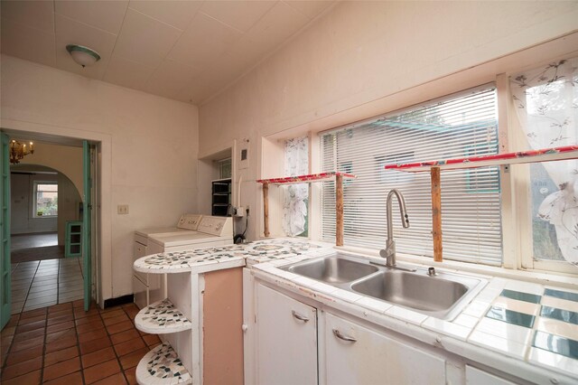 kitchen with dark tile patterned floors, plenty of natural light, white cabinetry, and sink