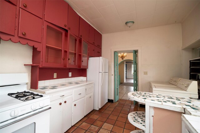 kitchen featuring dark tile patterned floors, independent washer and dryer, and white appliances