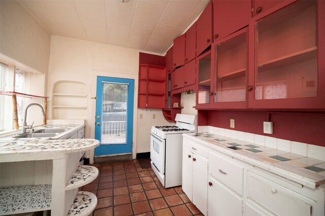 kitchen with white gas range oven, white cabinets, and sink