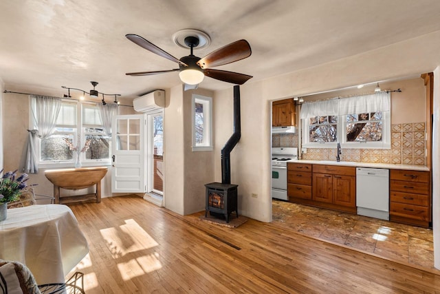 kitchen with a wood stove, a healthy amount of sunlight, light hardwood / wood-style floors, and white appliances