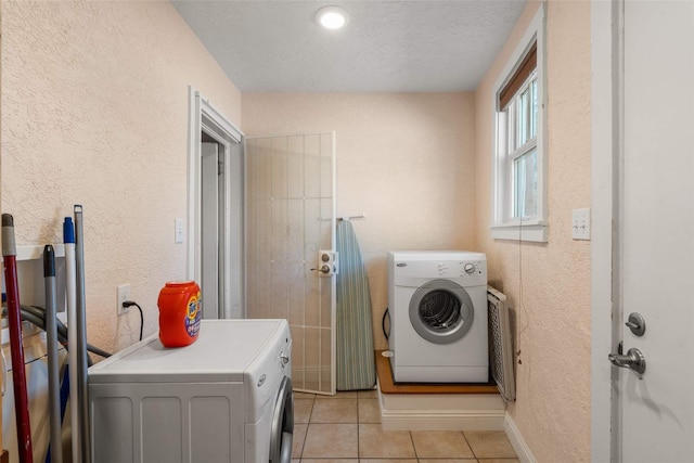 laundry area with washing machine and dryer, light tile patterned flooring, and a textured ceiling