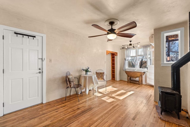 interior space featuring a wood stove, ceiling fan, and light hardwood / wood-style floors