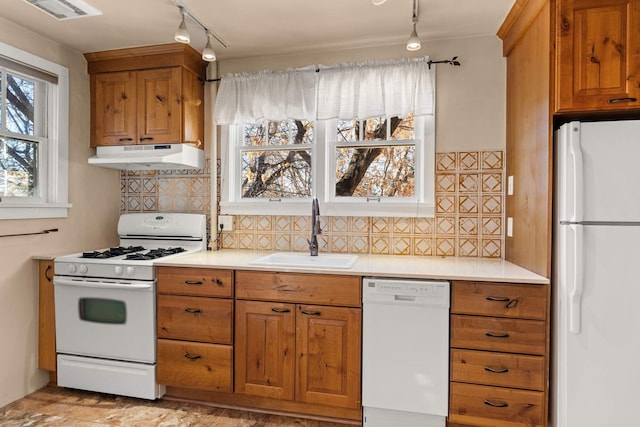 kitchen with backsplash, sink, rail lighting, and white appliances