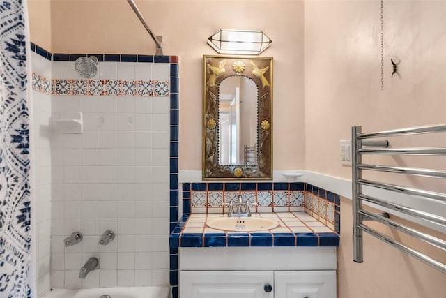 bathroom featuring radiator heating unit, vanity, and tiled shower / bath combo