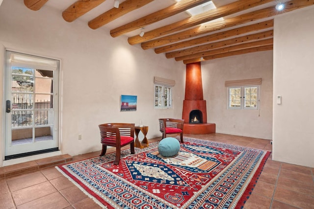 living area featuring tile patterned flooring, beam ceiling, a large fireplace, and a wealth of natural light