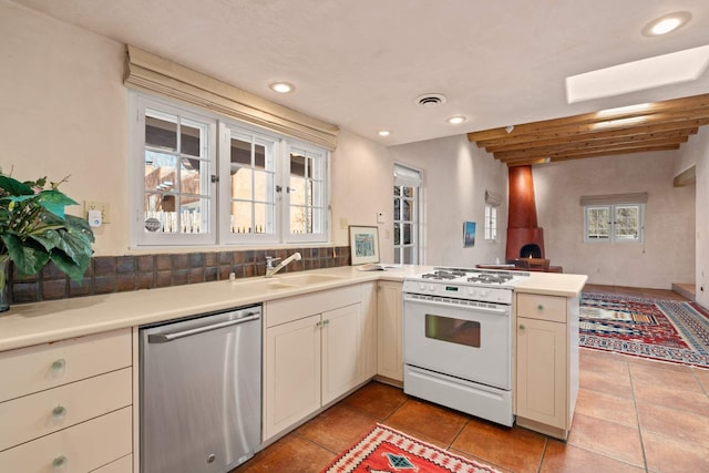 kitchen with kitchen peninsula, white range oven, sink, dishwasher, and light tile patterned flooring