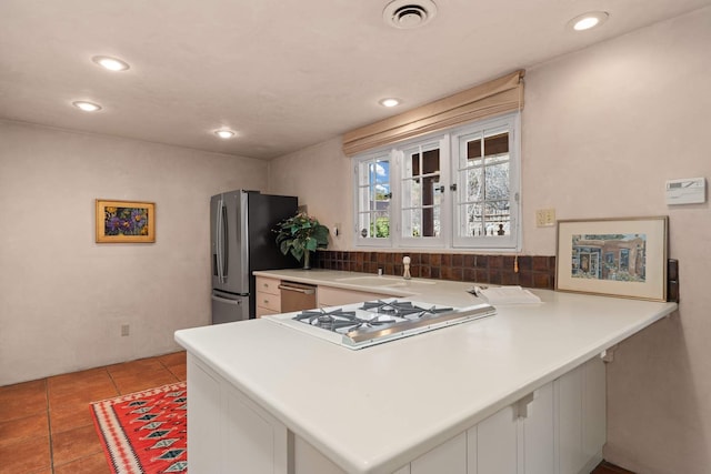 kitchen with kitchen peninsula, appliances with stainless steel finishes, tasteful backsplash, and sink