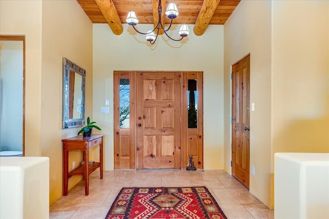 foyer entrance featuring beam ceiling, light tile patterned flooring, wooden ceiling, and an inviting chandelier