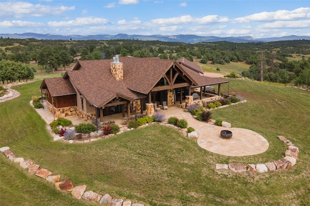 view of front facade with a patio area, a mountain view, and a front yard