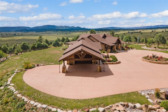 exterior space with a yard, curved driveway, a mountain view, fence, and a rural view