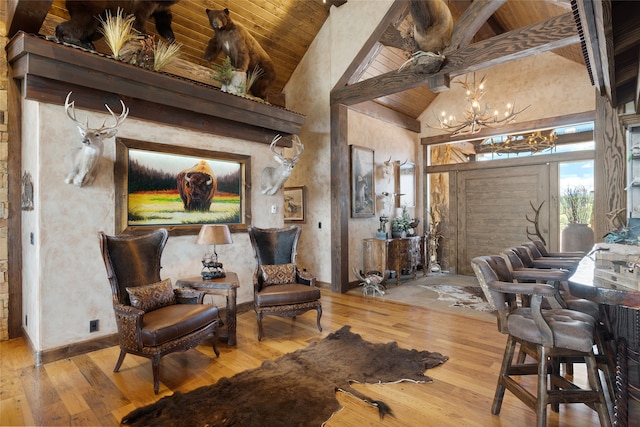 living area with beam ceiling, an inviting chandelier, wood finished floors, high vaulted ceiling, and wooden ceiling