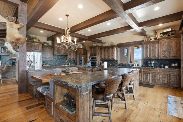 kitchen featuring decorative backsplash, light hardwood / wood-style flooring, beamed ceiling, and a large island