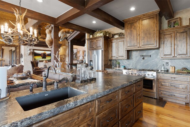 kitchen with light hardwood / wood-style flooring, sink, beamed ceiling, dark stone countertops, and premium appliances