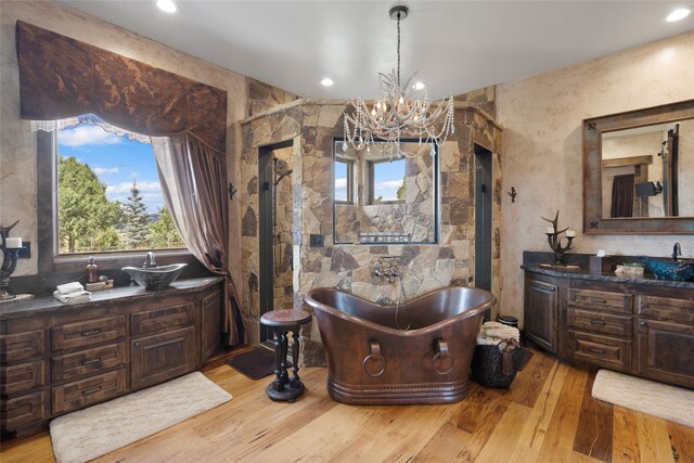 bathroom with hardwood / wood-style floors, a bathtub, a notable chandelier, and vanity