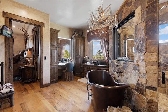 full bath featuring wood-type flooring, a freestanding tub, and a notable chandelier