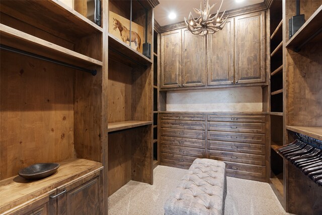 spacious closet featuring light colored carpet and an inviting chandelier