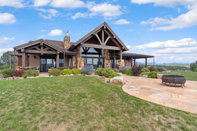 view of front of house featuring a front lawn, a fire pit, and a patio area