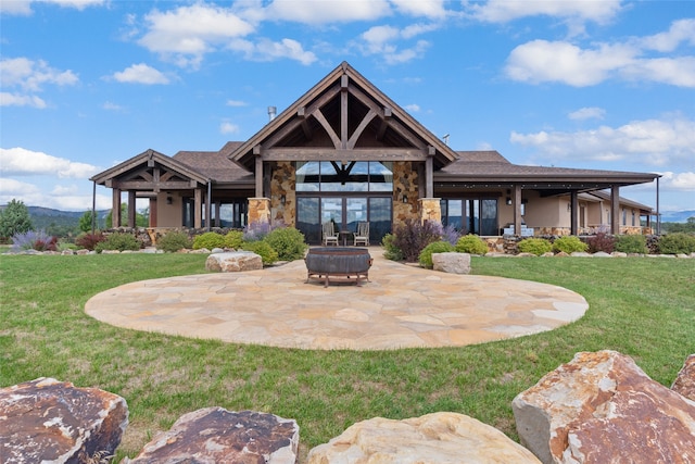 back of house featuring stone siding, a patio area, a lawn, and stucco siding